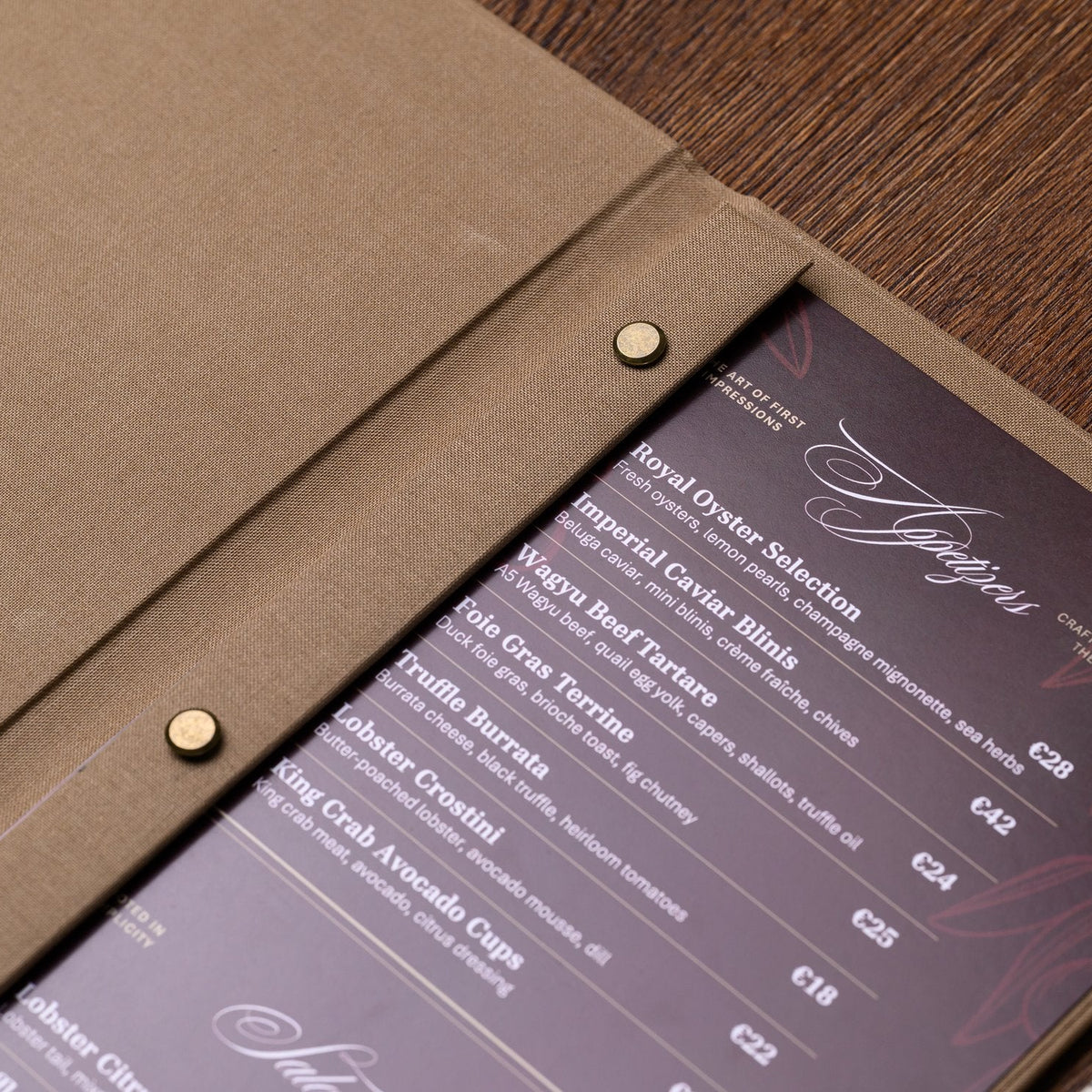 Open taupe textile menu folder shown from the side with a dark page of white script text and a bar rail