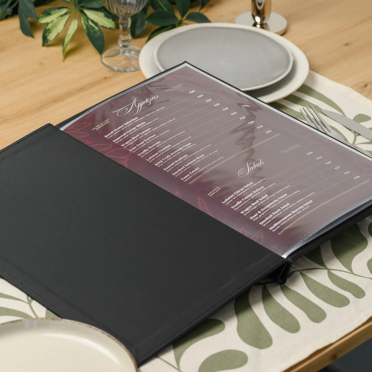 Open black textured faux leather menu cover on a set restaurant table with a printed menu page in a clear sleeve