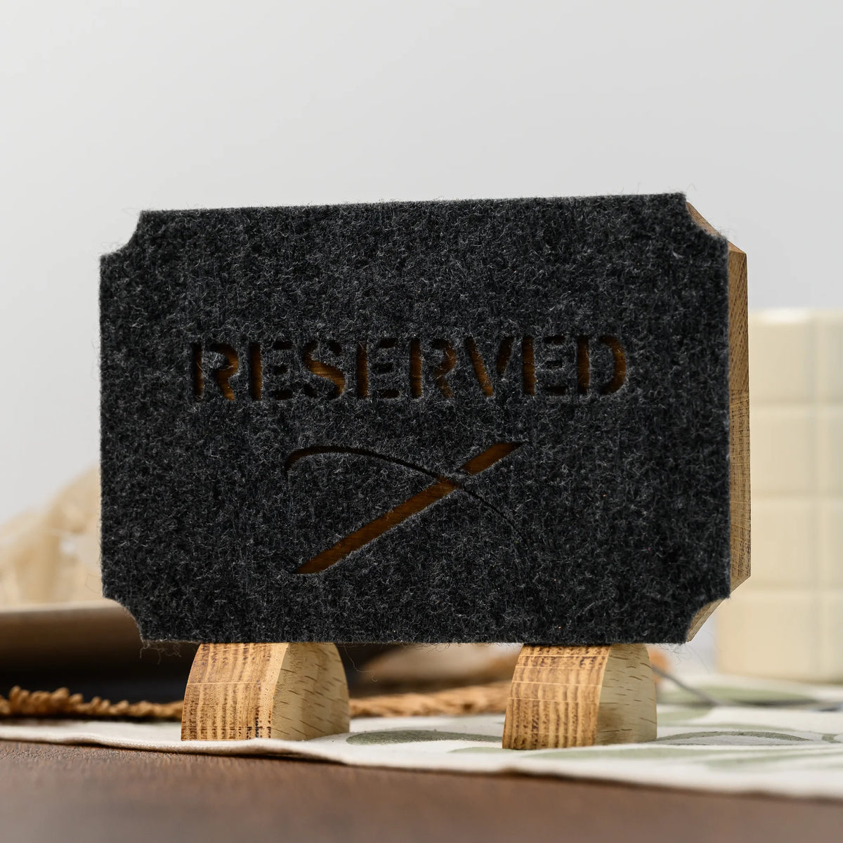 A close-up of a Reserved table sign showing its die-cut felt lettering set against the oak panel below