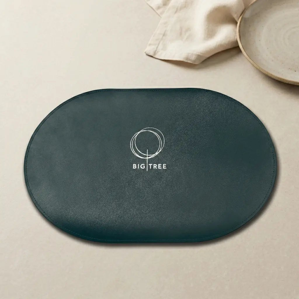 Dark green oval placemat with 'BIG TREE' logo on a beige surface.