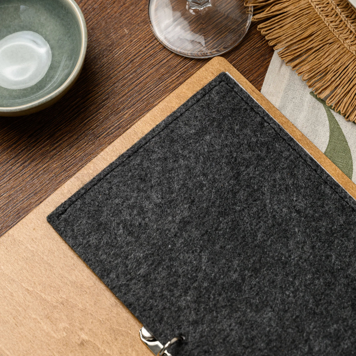 A close-up of the felt cover stitched edge on a plywood menu board resting on a set restaurant table