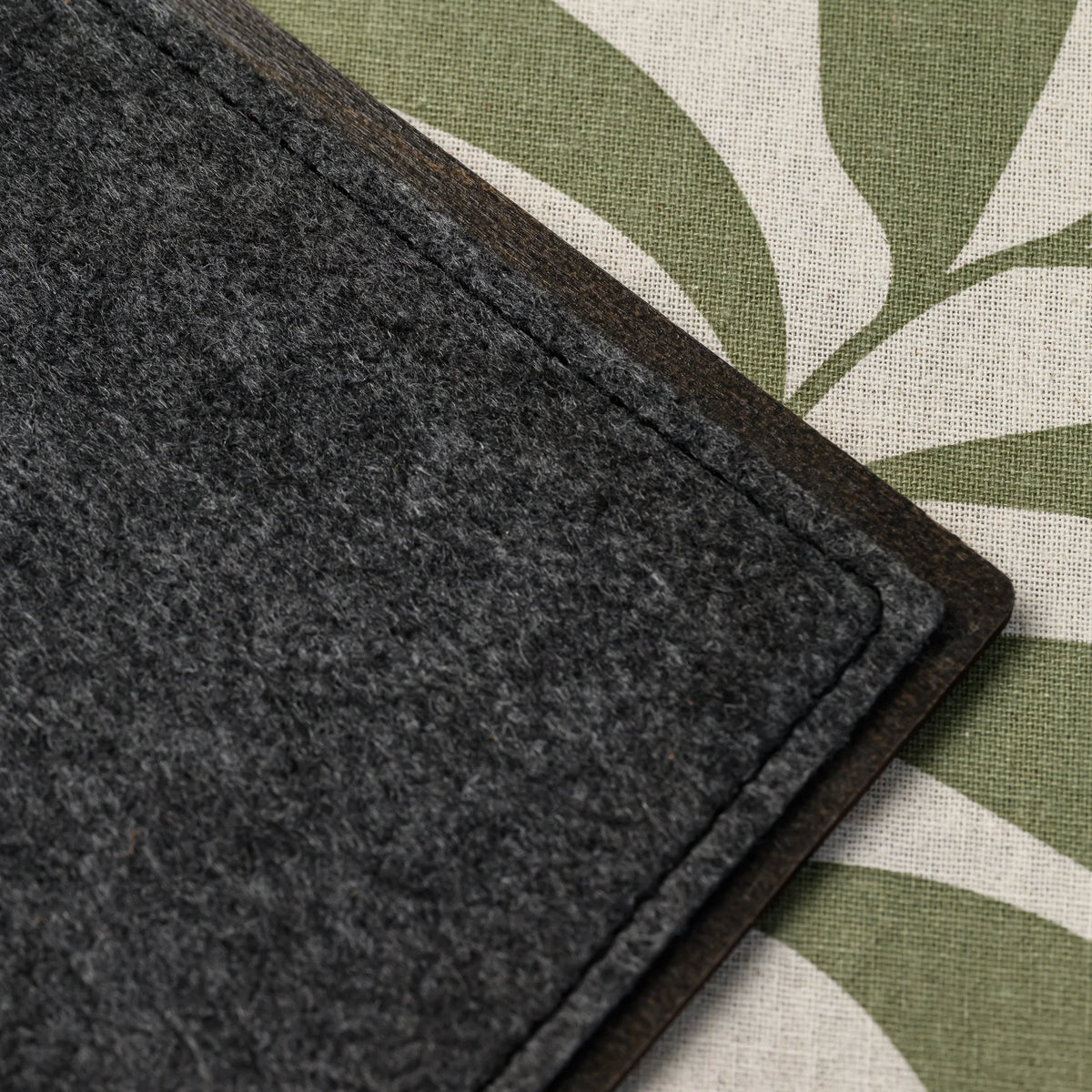 A macro view of the stitched felt edge and wooden trim on the corner of a felt-front menu board, close