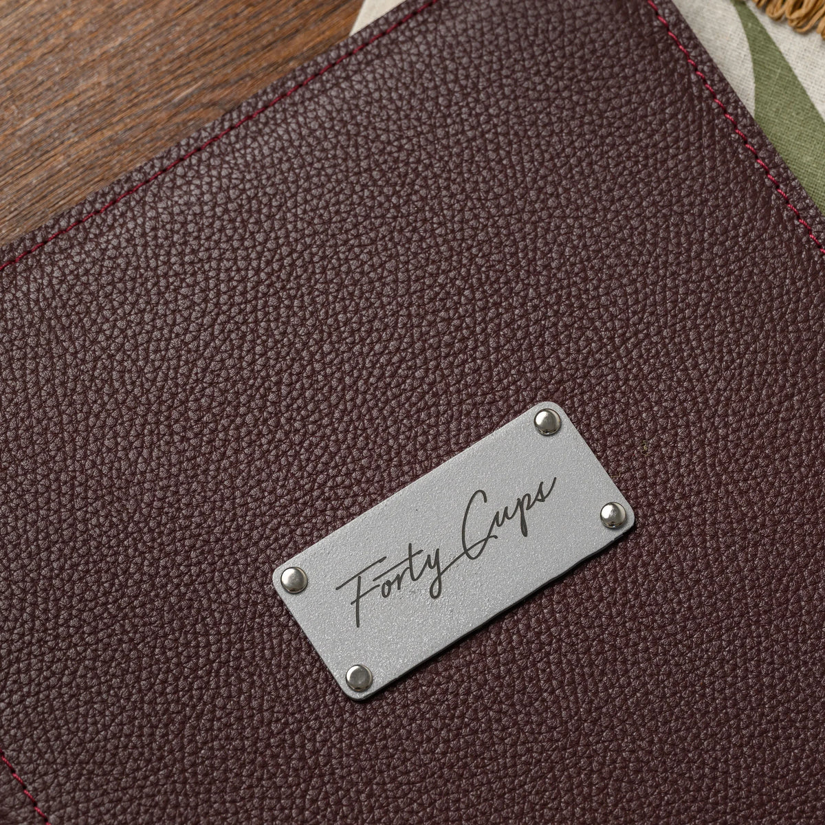 Macro of a rectangular silver metal plate with engraved script lettering fixed by four rivets on bordeaux leather