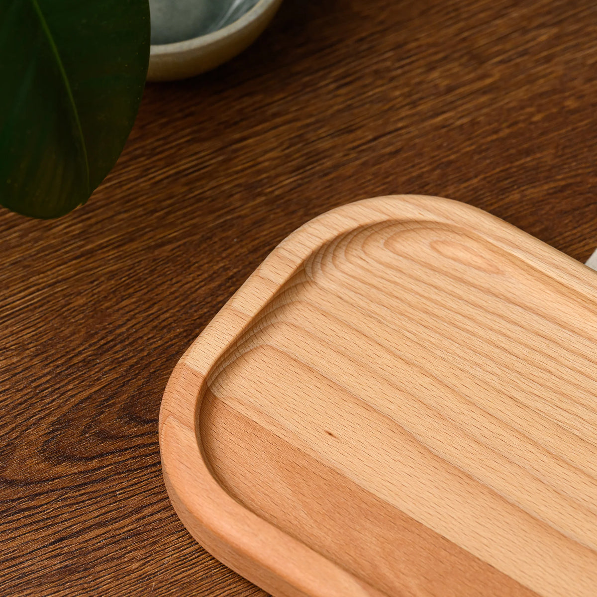 Angled close-up of an empty beech wood rectangular serving board showing its raised rim and wood grain