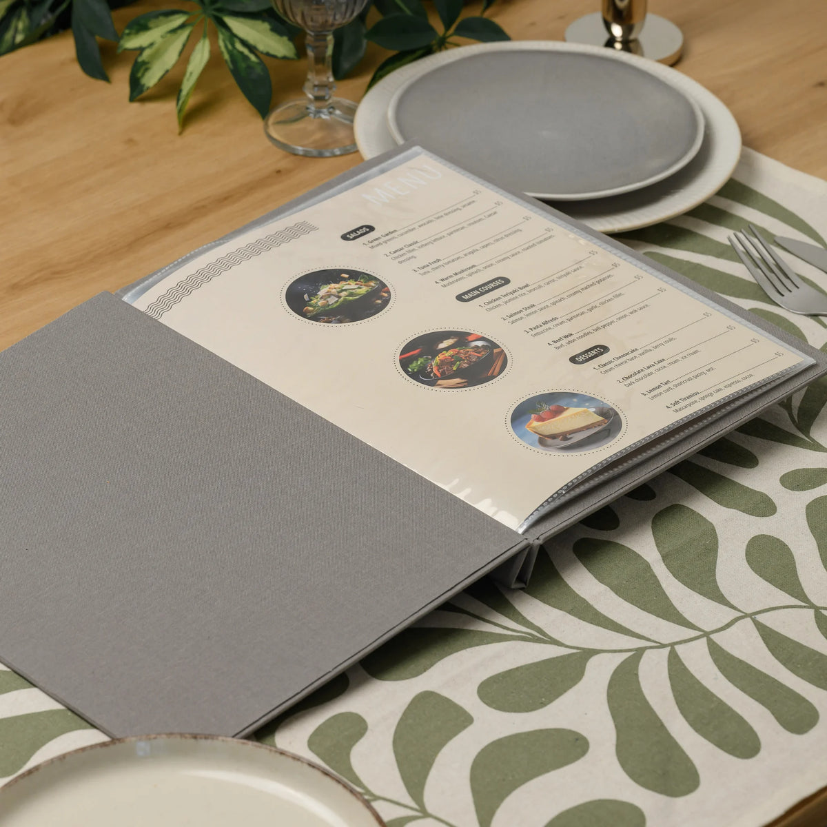Open gray fabric menu cover on a restaurant table with a printed food menu inside a clear plastic sleeve