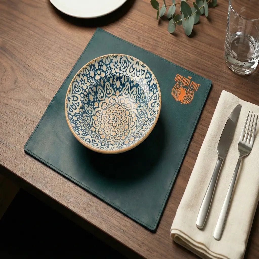Decorative ceramic bowl on a green placemat with cutlery and water glass on a wooden table.