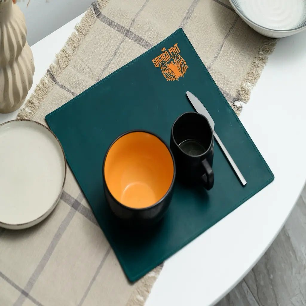 Teal placemat with orange and black mugs on a checkered tablecloth