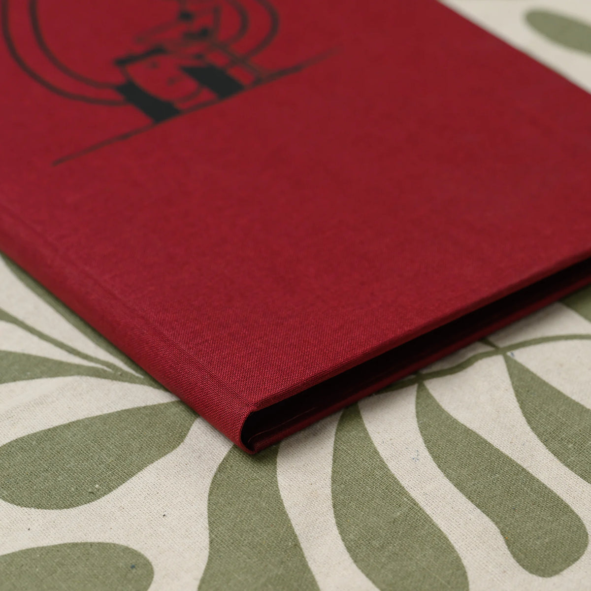 Close-up of the rounded spine and folded edge of a closed red fabric menu cover showing the fine woven texture
