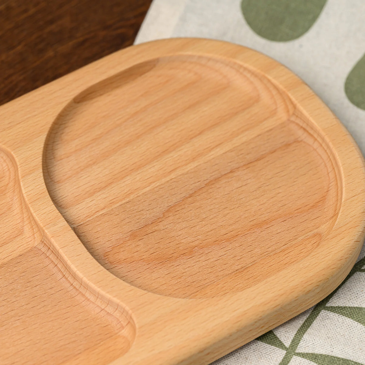 Close-up overhead view of the rounded divider between two oval compartments on the beech wood serving board
