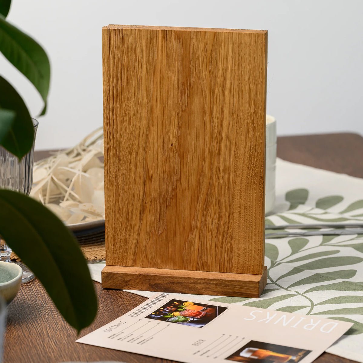 The back of a freestanding oak table tent, standing upright on its base beside a printed menu page nearby