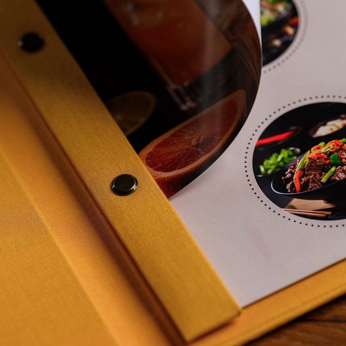 Open mustard-yellow textile menu folder shown from the side with a bar binding rail and a drink photo insert