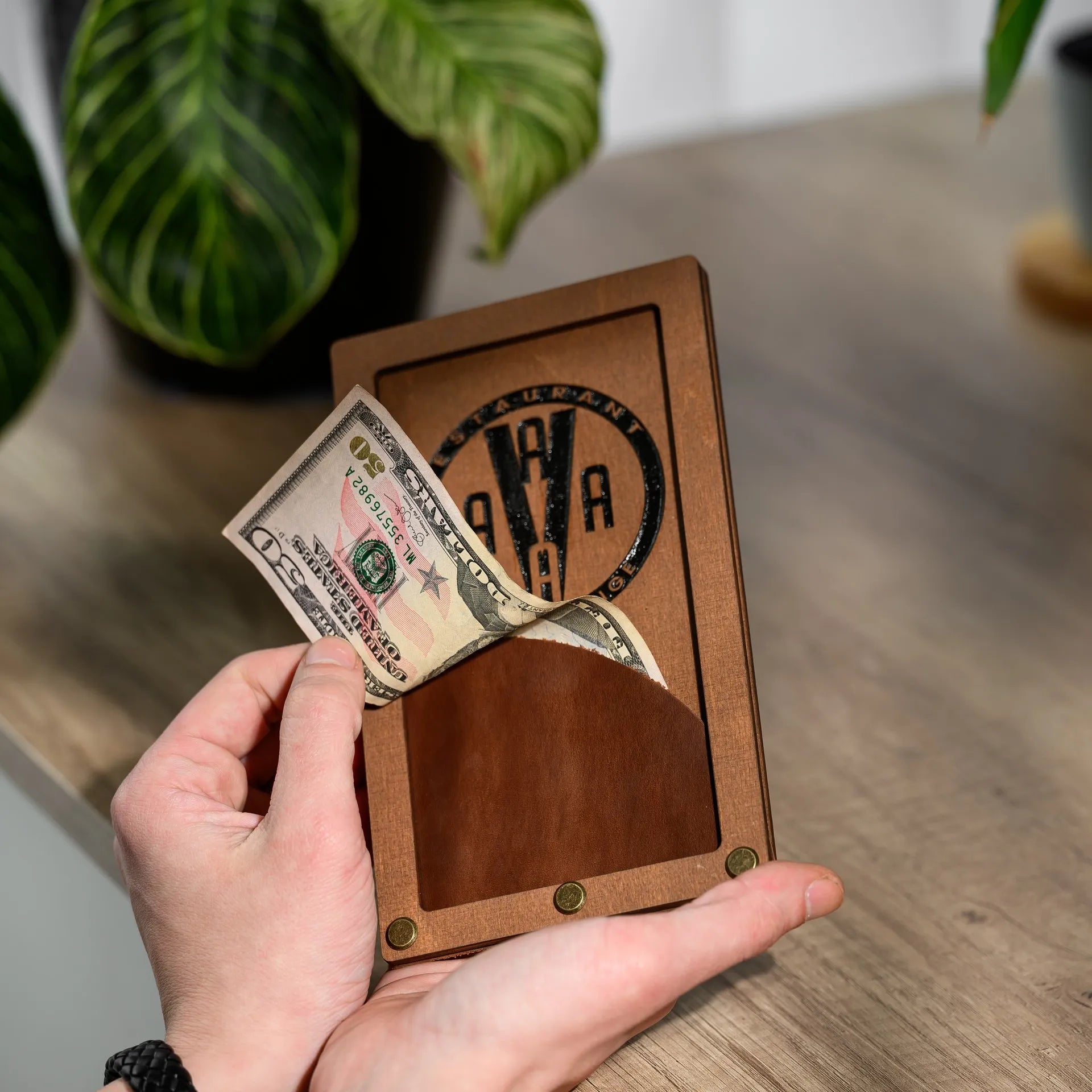 Wooden bill holder with logo engraving, reflecting the restaurant's branding.