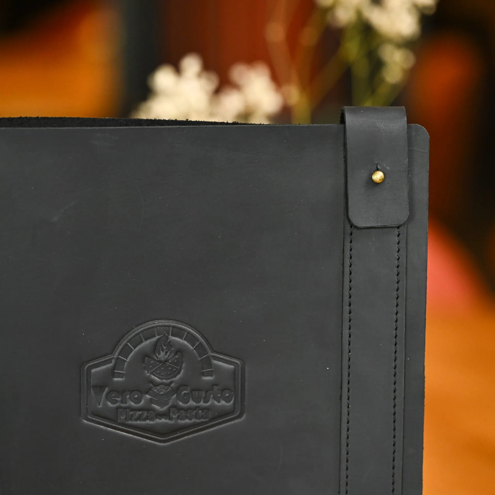 Premium leather menu holder featuring custom logo embossing and a rubber strip for securely binding half A3 sheets. Sleek and durable design.