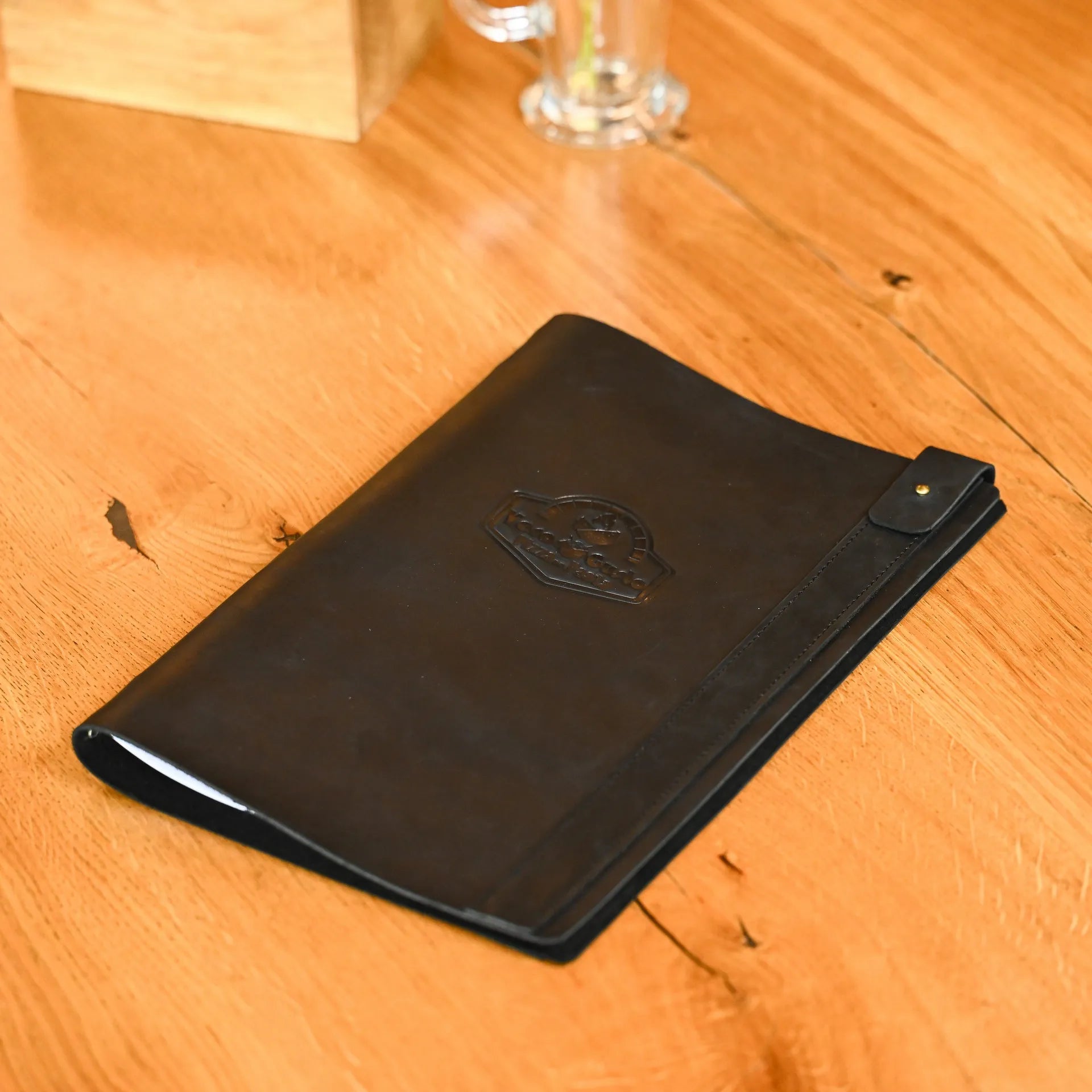 Custom menu folder made from premium leather with rubber strip binding, perfect for holding half A3 sheets. Embossed logo adds a stylish touch.