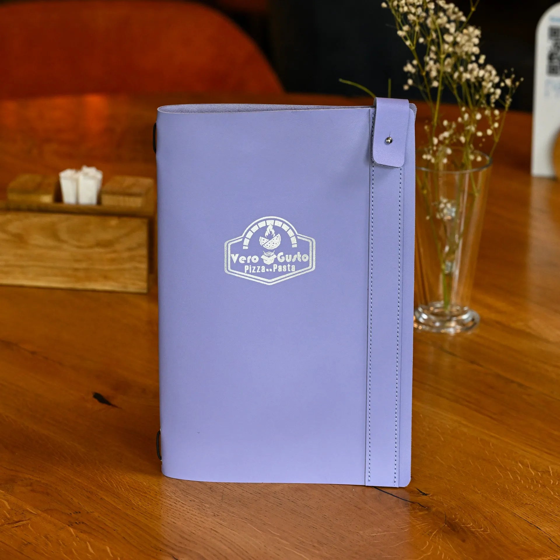 Soft leather drink menu holder with an elastic strap for easy sheet changes and a custom logo for a sleek, branded presentation.