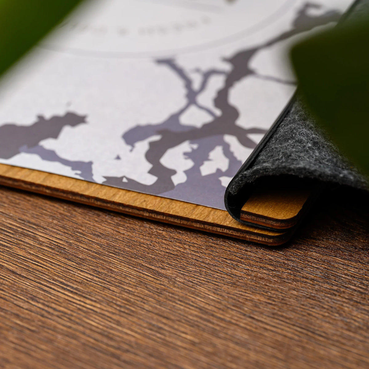 A close-up of a felt menu folder cover peeling back to reveal the layered plywood core edge underneath