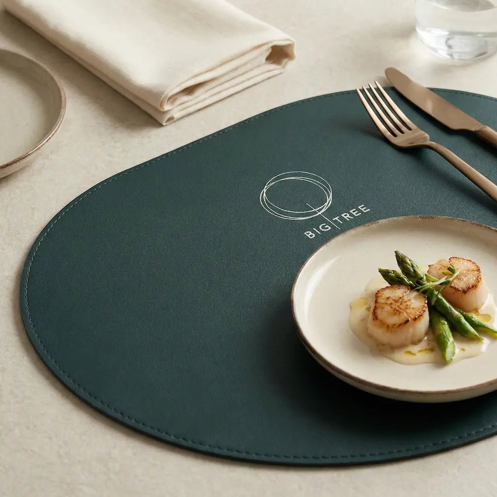 Green placemat with a plate of food and cutlery on a table setting.