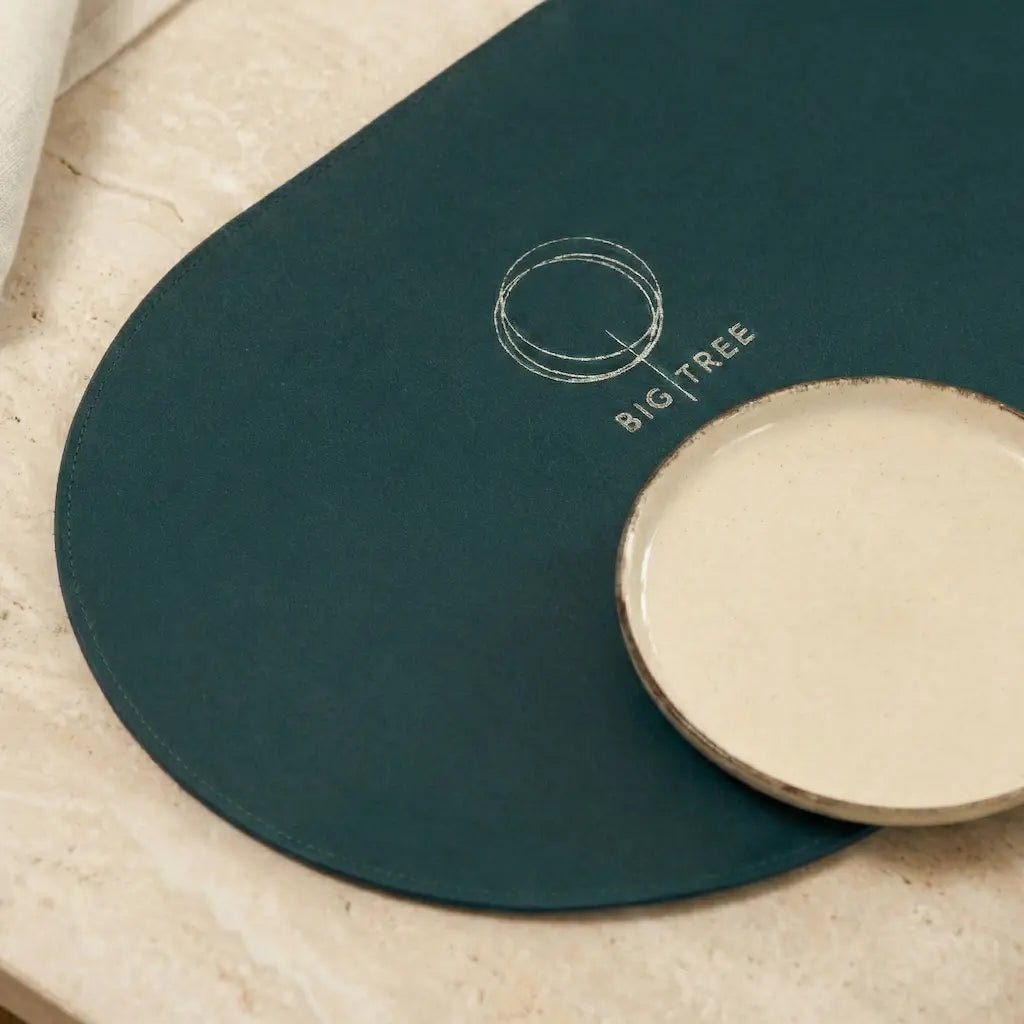 Teal placemat with 'BIG TREE' logo on a wooden surface
