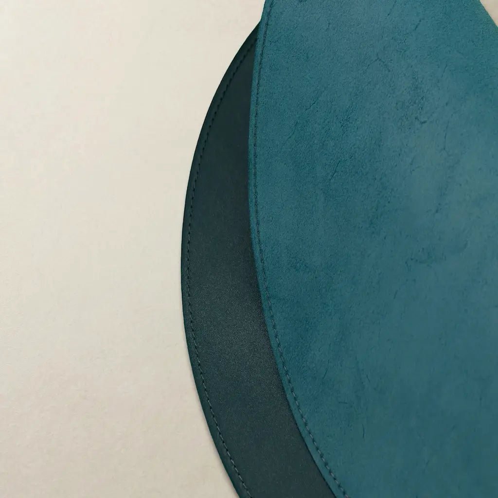 Close-up of a teal leather product on a beige background