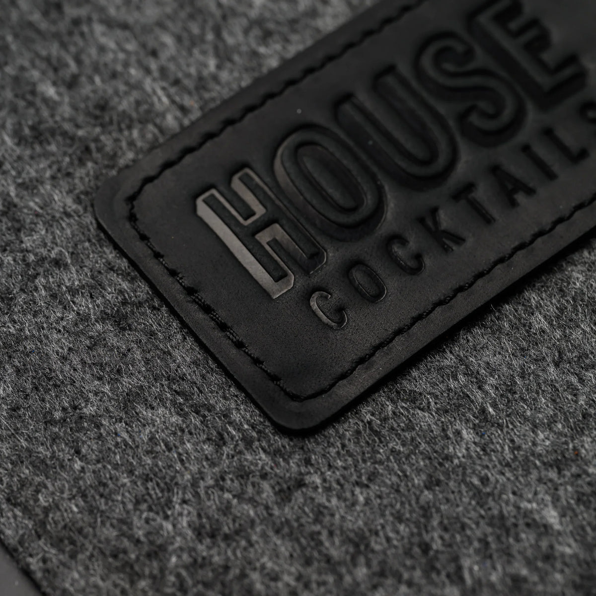 A macro view of a blind-embossed leather patch sewn directly onto the felt cover of this menu folder