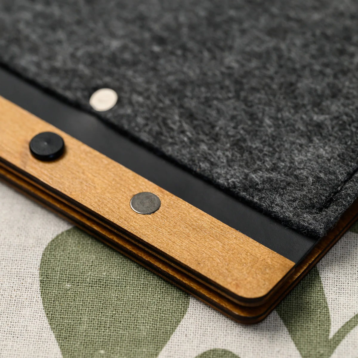 A macro view of the wood spine rivets and felt cover edge on the leather-bound menu folder, seen at an angle