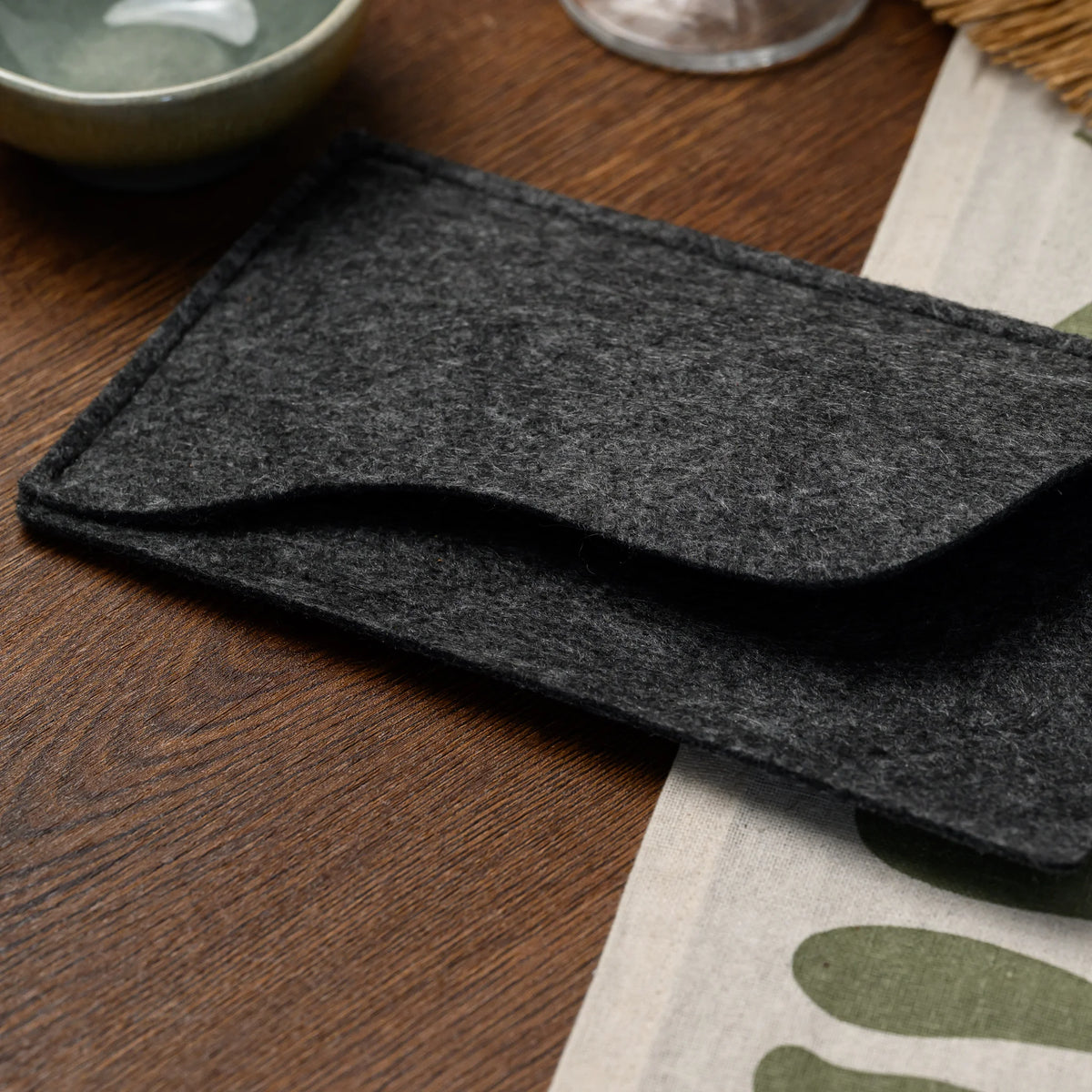 A macro view of the empty wavy-edged pocket on a felt bill presenter, resting on a wood tabletop closely