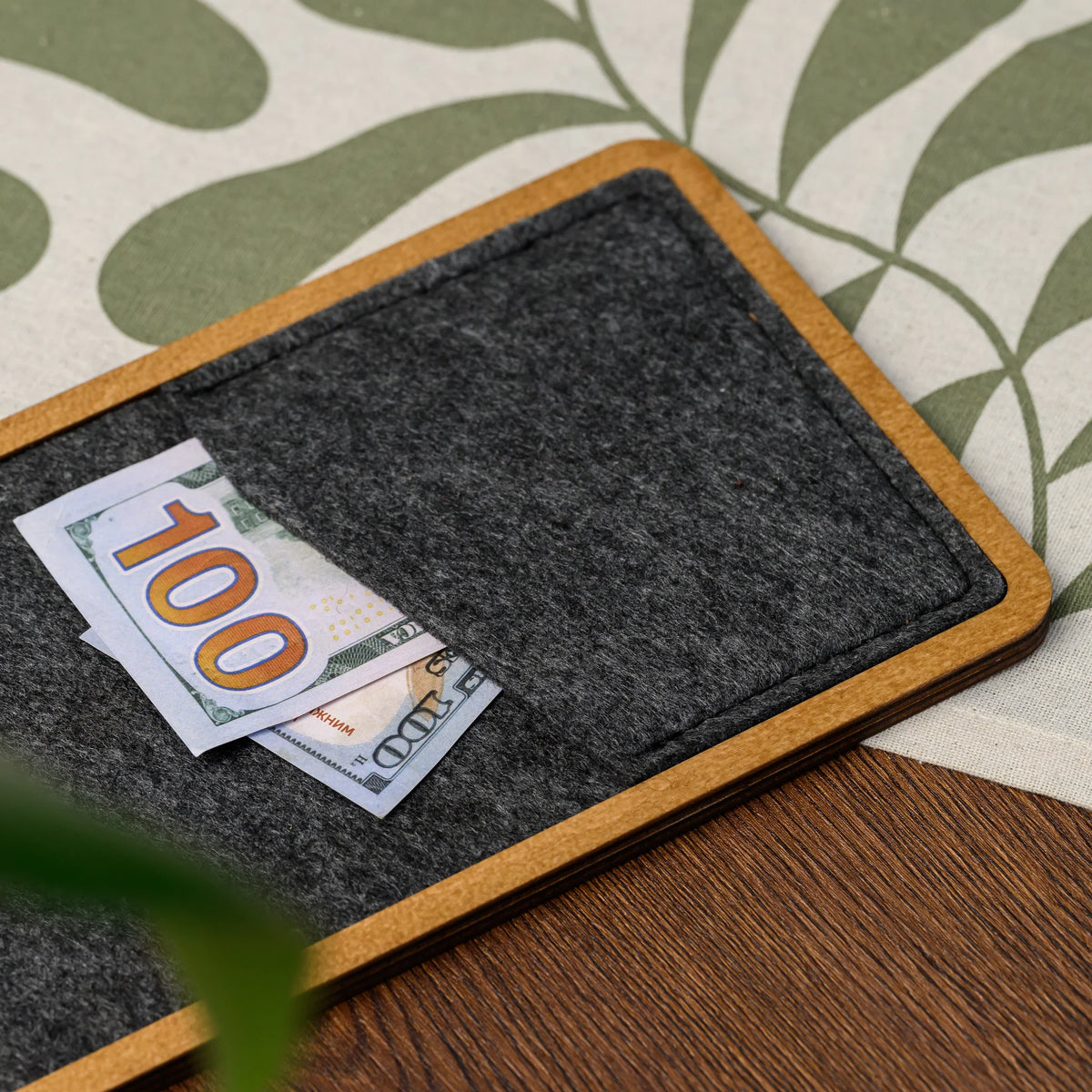 A close-up of a banknote inside the felt pocket of a bill presenter, resting on a patterned tablecloth 