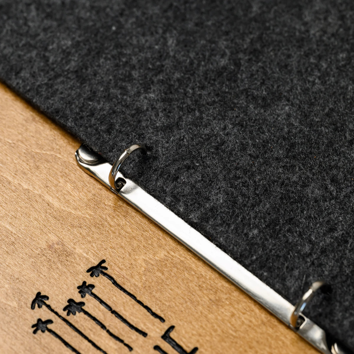 A macro view of the two metal rings holding a printed menu page in place on the plywood board surface 
