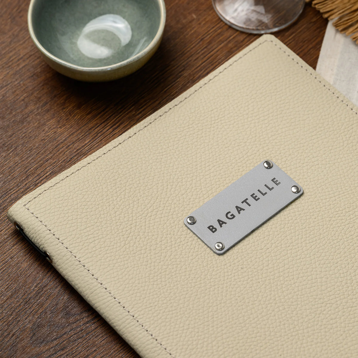 Close-up of beige leather cover with riveted silver plate and elastic cord with eyelets along the spine edge