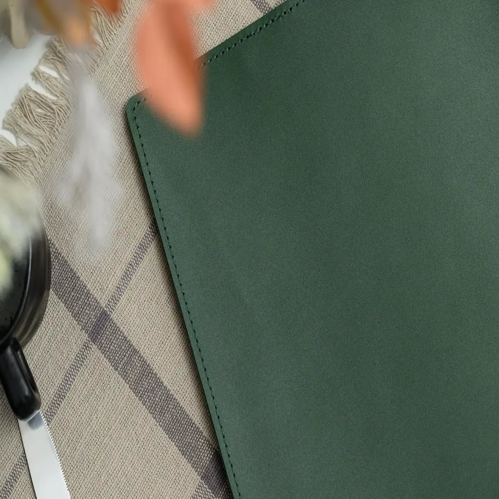 Green leather wallet on a checkered fabric surface