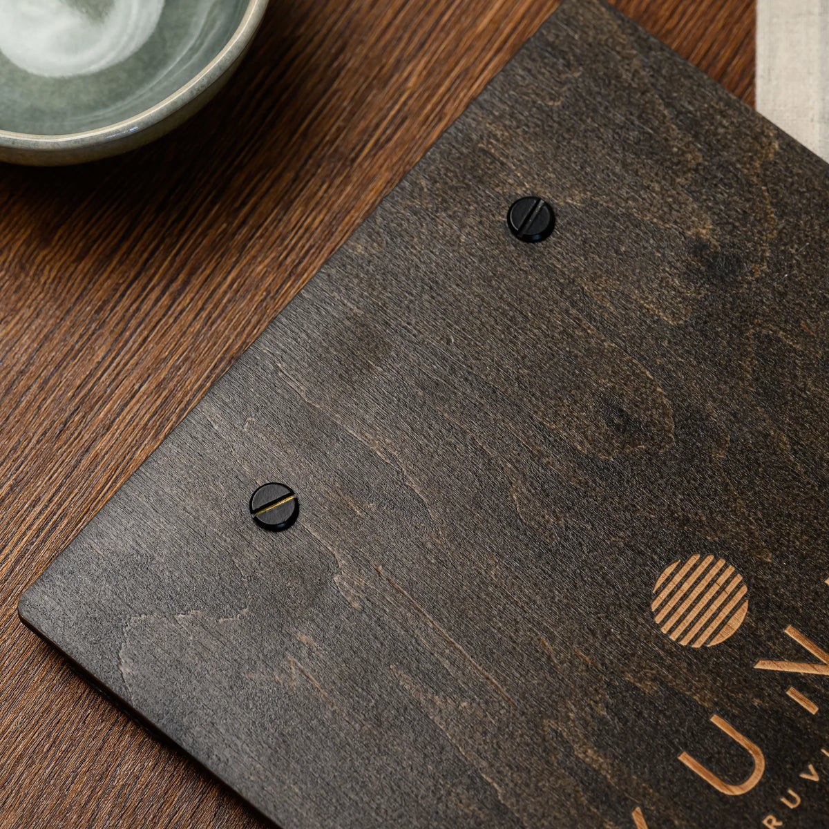 A macro view of two black screws fastening the wooden clamp bar to the top of this menu board closely 