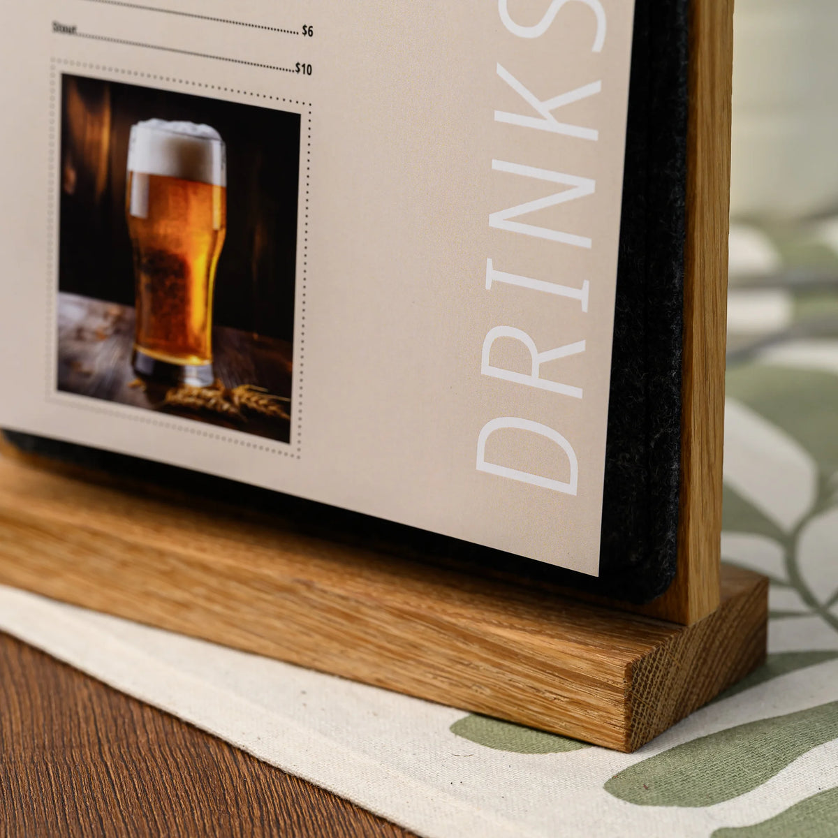 A close-up of the base of a table tent, showing a printed beer menu page against the charcoal felt panel 