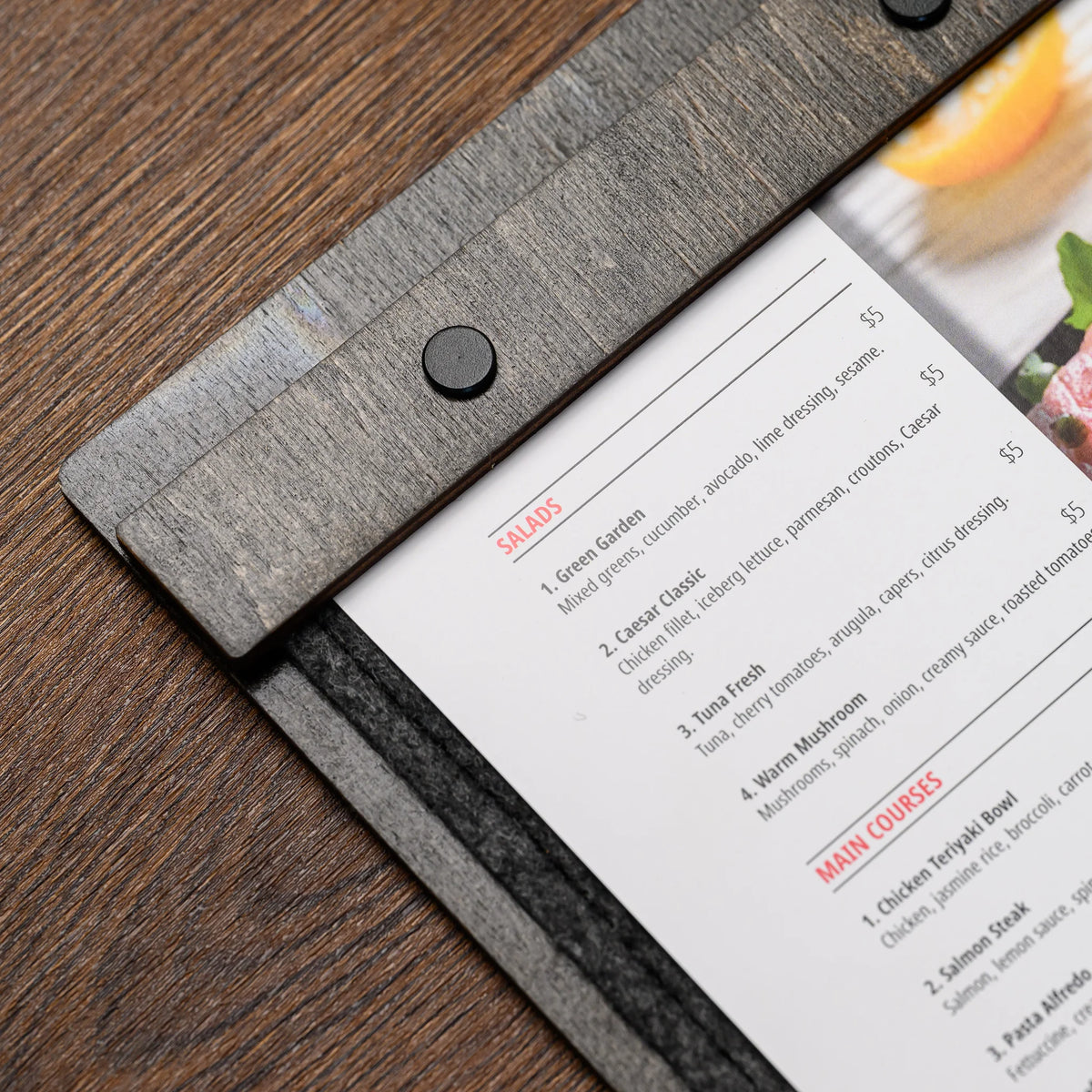 The reverse side of a felt-front menu board, resting flat on a wood table with its engraved logo shown 
