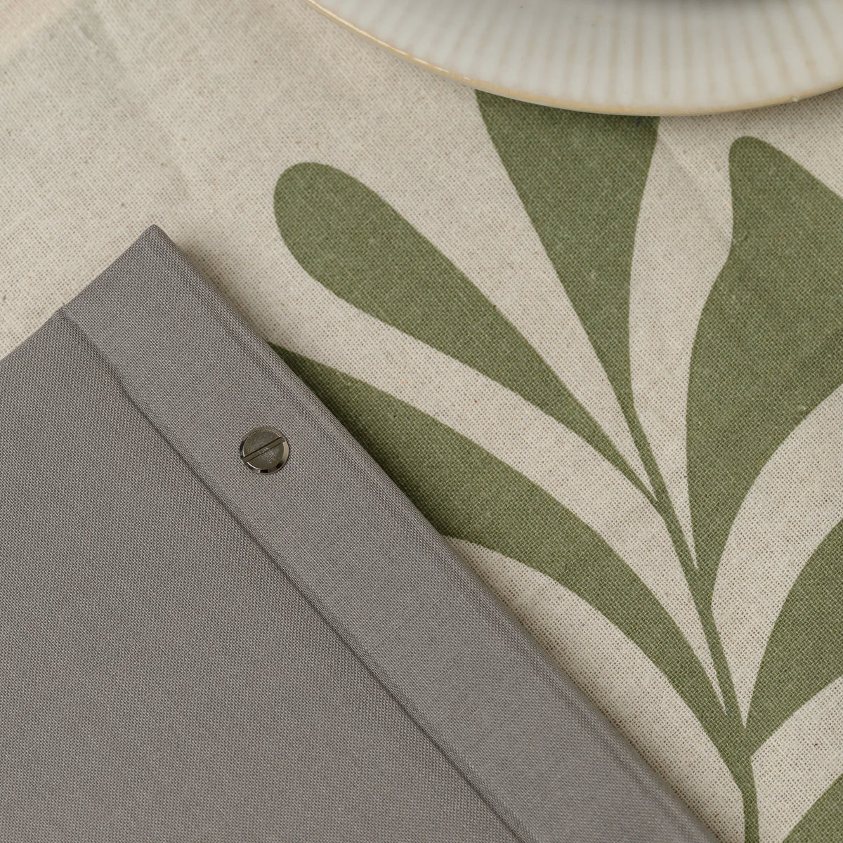 Macro view of a slotted chrome screw on the spine of a gray menu cover showing the fine woven fabric texture