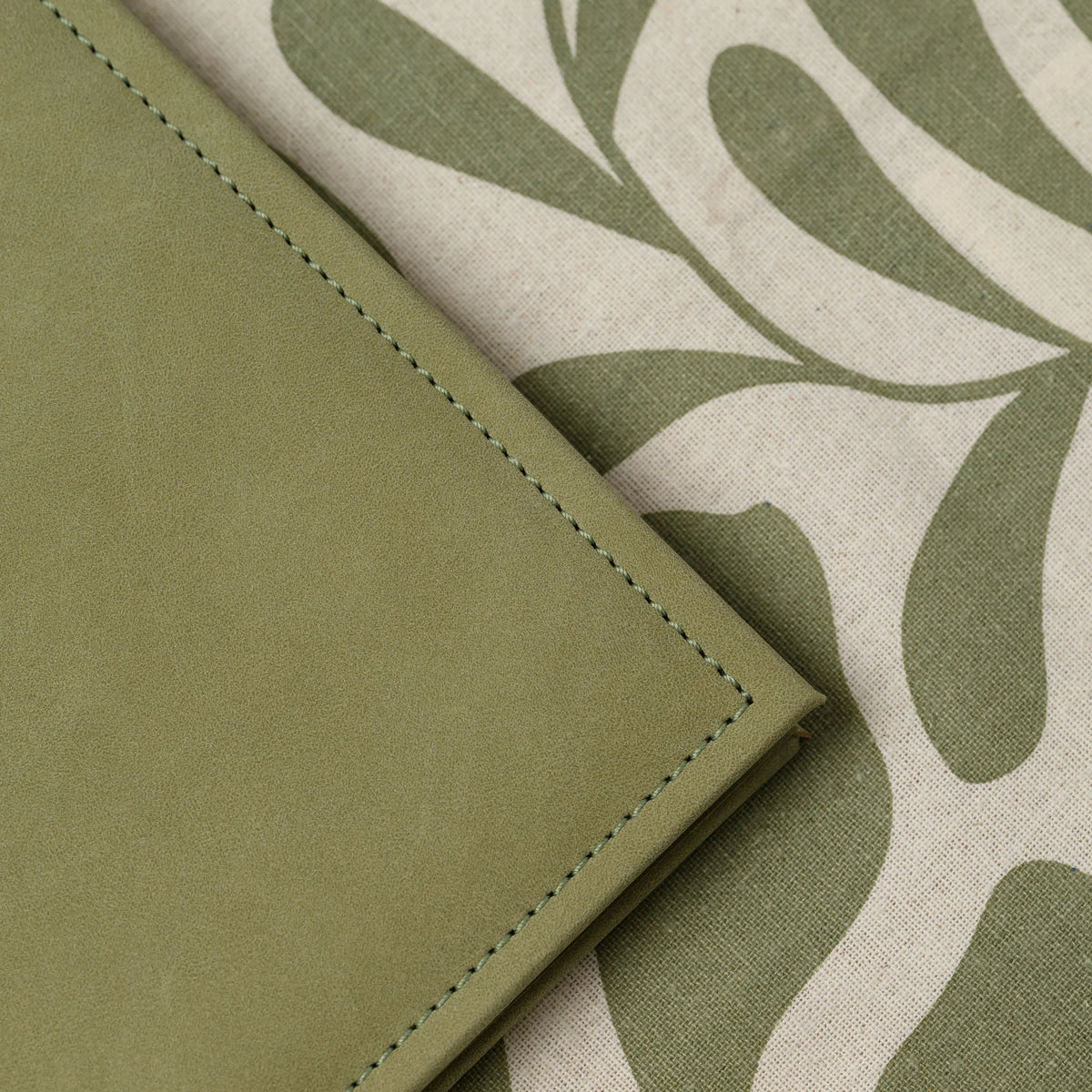 Macro view of the stitched corner of an olive Nubuk faux leather menu cover with a soft brushed matte surface