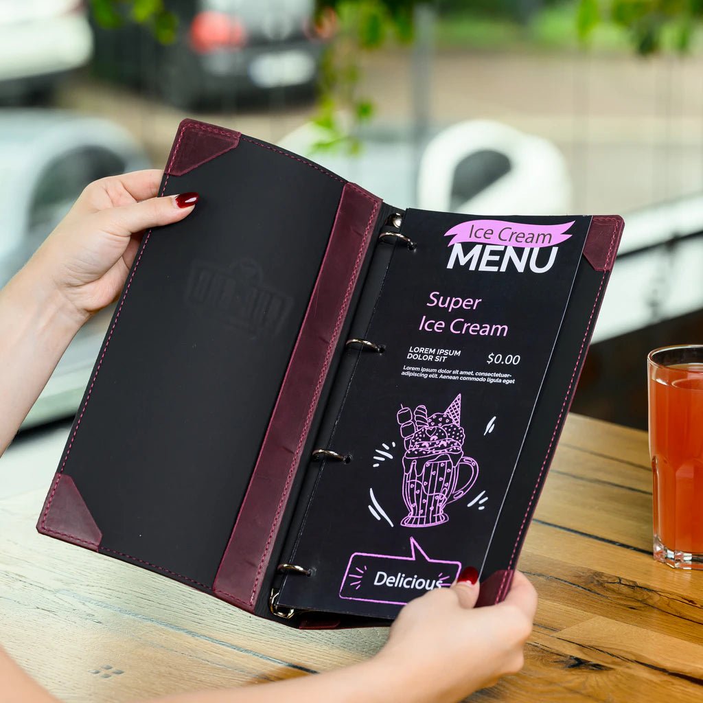 Person holding a menu with a blurred outdoor cafe background