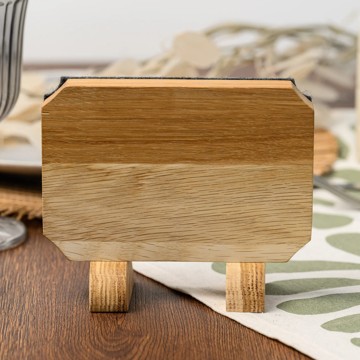The back of a Reserved table sign, showing the oak panel and its two freestanding wooden stand legs closely 