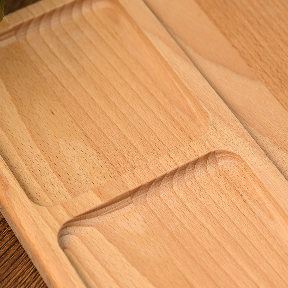 Close-up of the rounded groove dividing two compartments on the beech wood serving board, showing natural grain