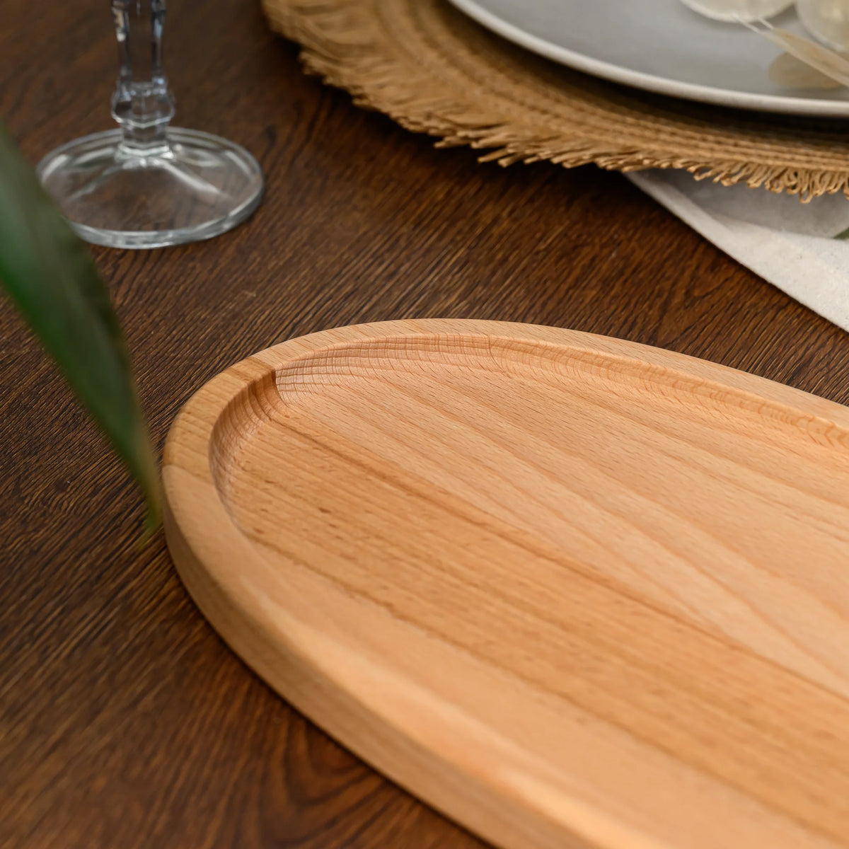 Angled close-up of an empty beech wood oval serving board showing its full length and raised rim