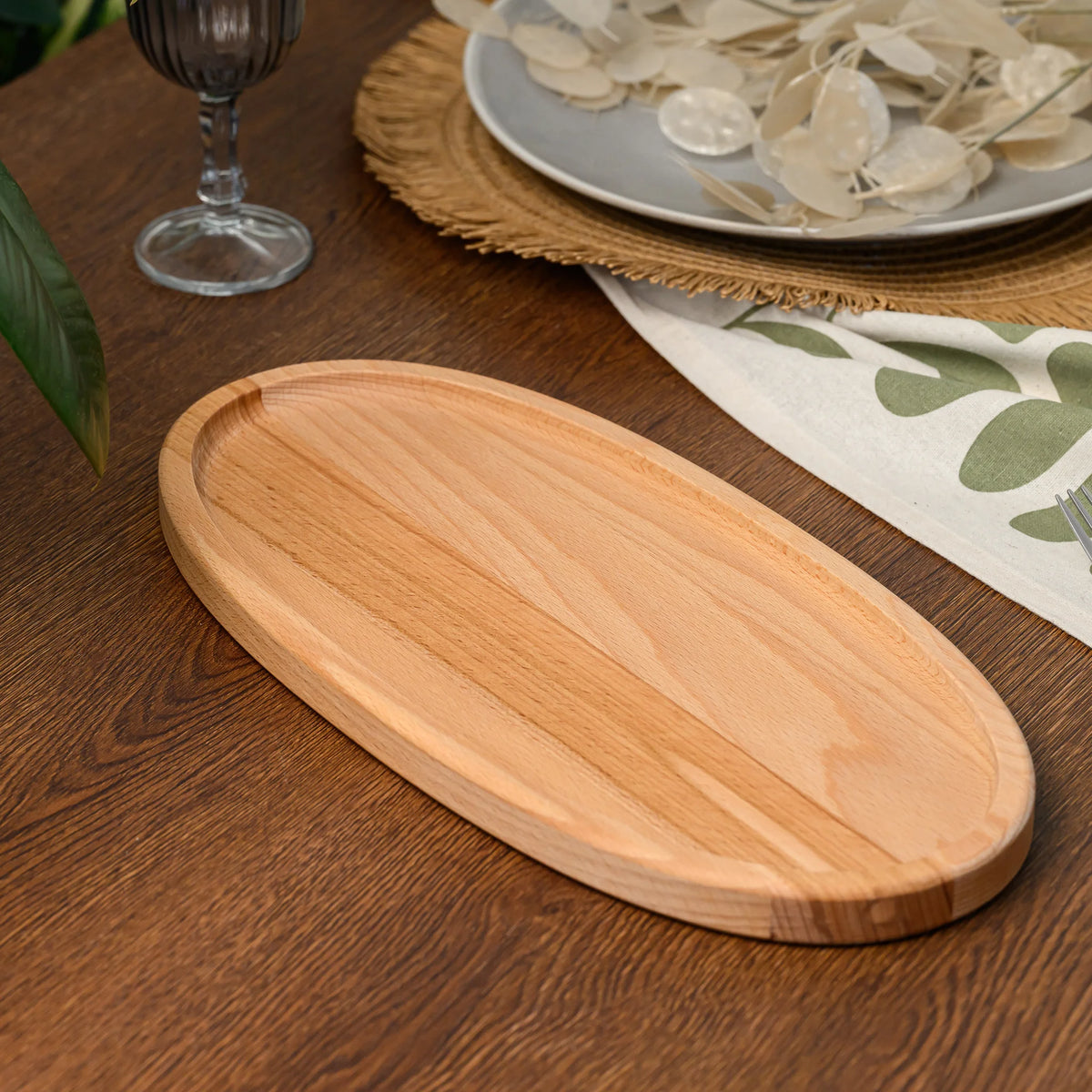 Angled close-up of an empty beech wood oval serving board showing its full length and raised rim