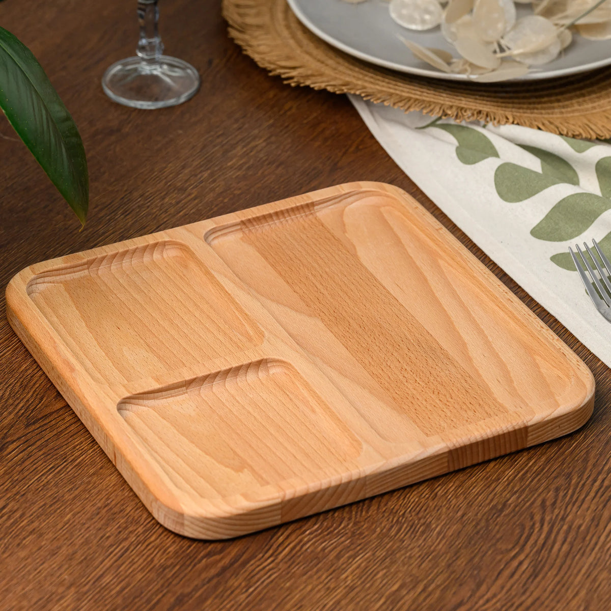 Angled top view of an empty three-compartment beech wood serving board placed on a dark wooden table