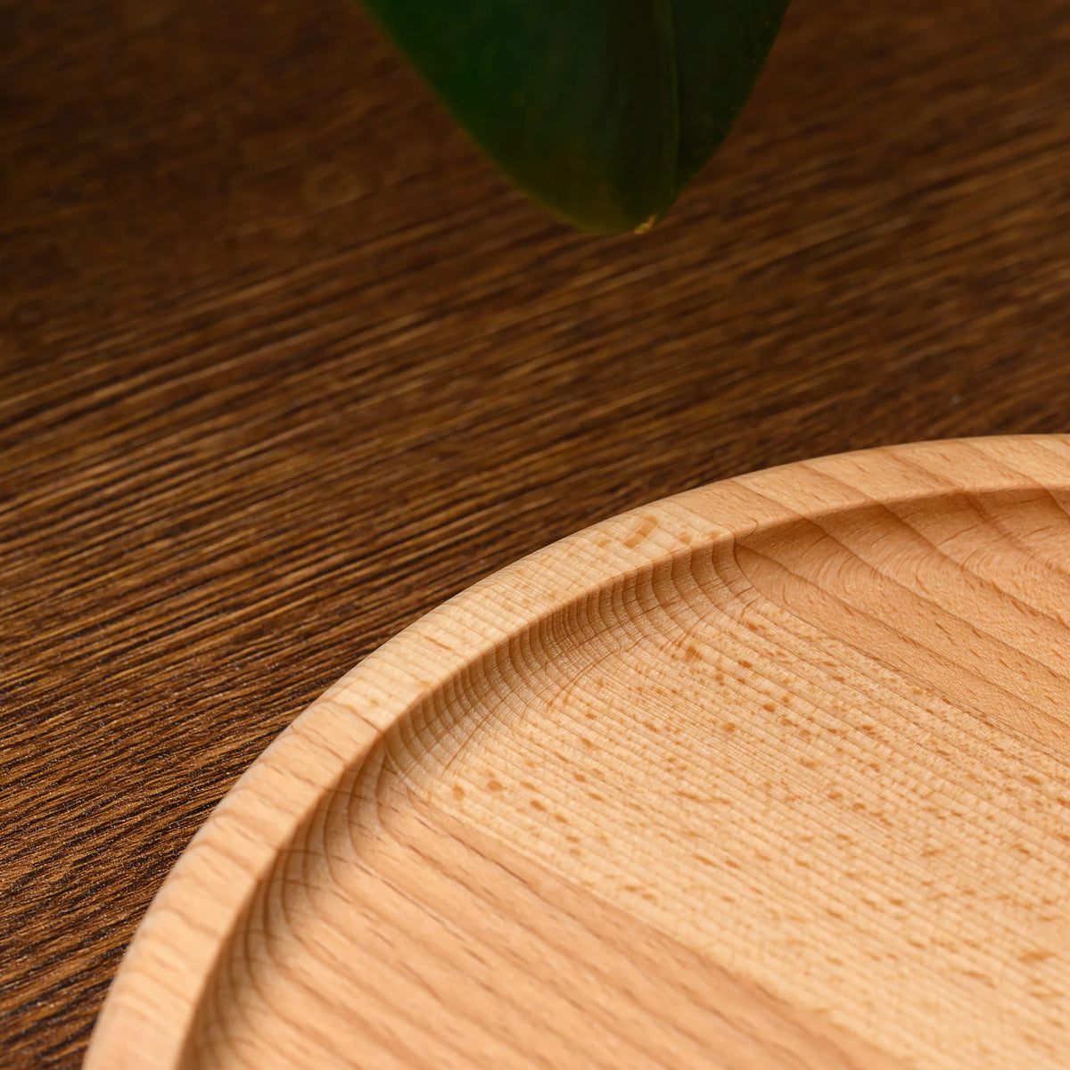 Close-up of the raised rim and natural wood grain along the edge of the round beech wood serving plate
