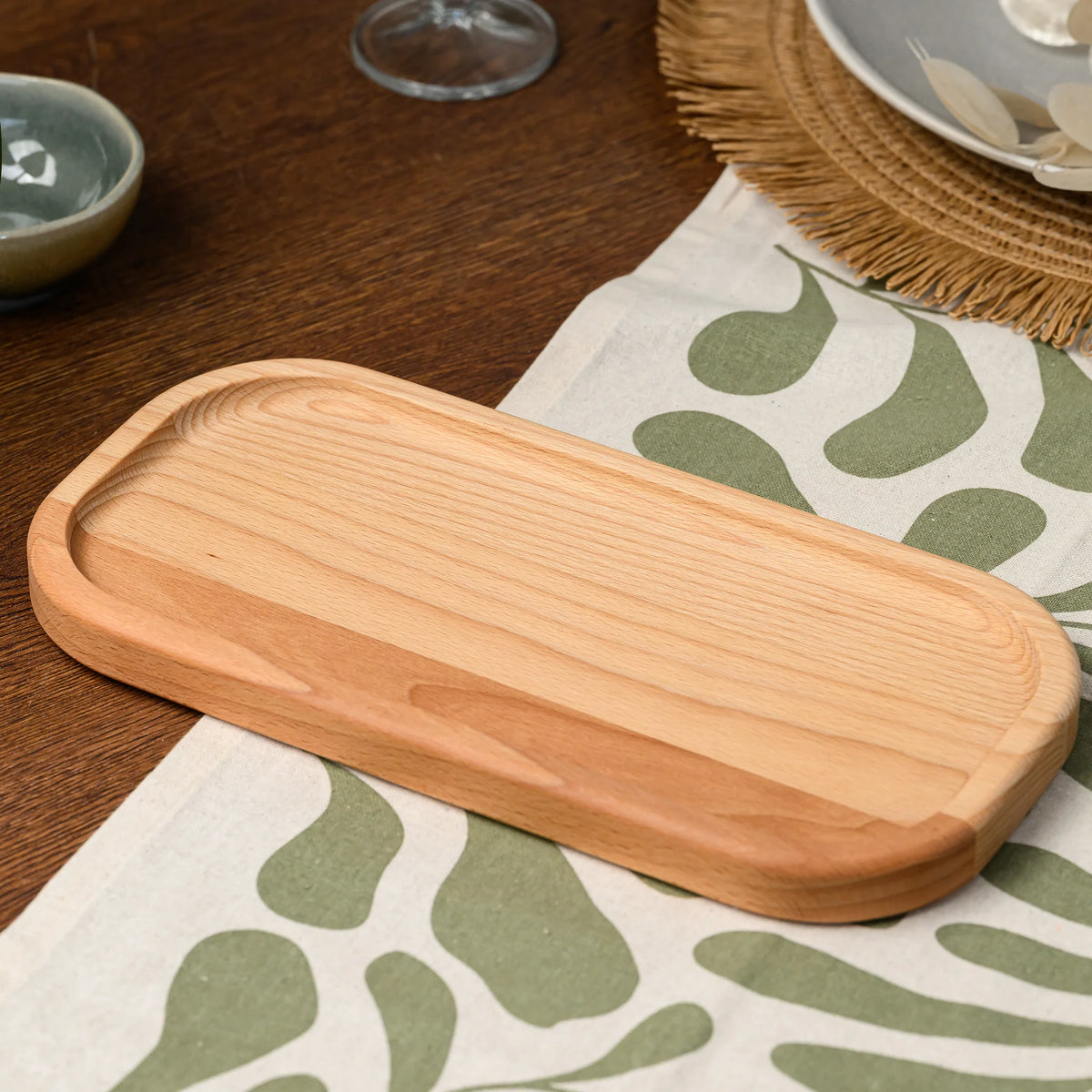Angled view of an empty beech wood rectangular serving board resting on a plain linen tablecloth
