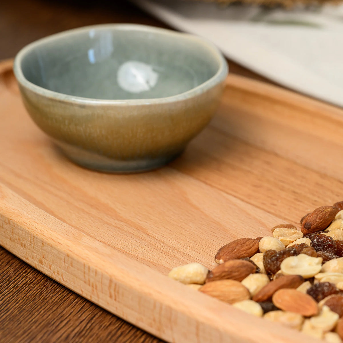Overhead view of the beech wood oval serving board styled with a ceramic bowl and a mix of whole nuts