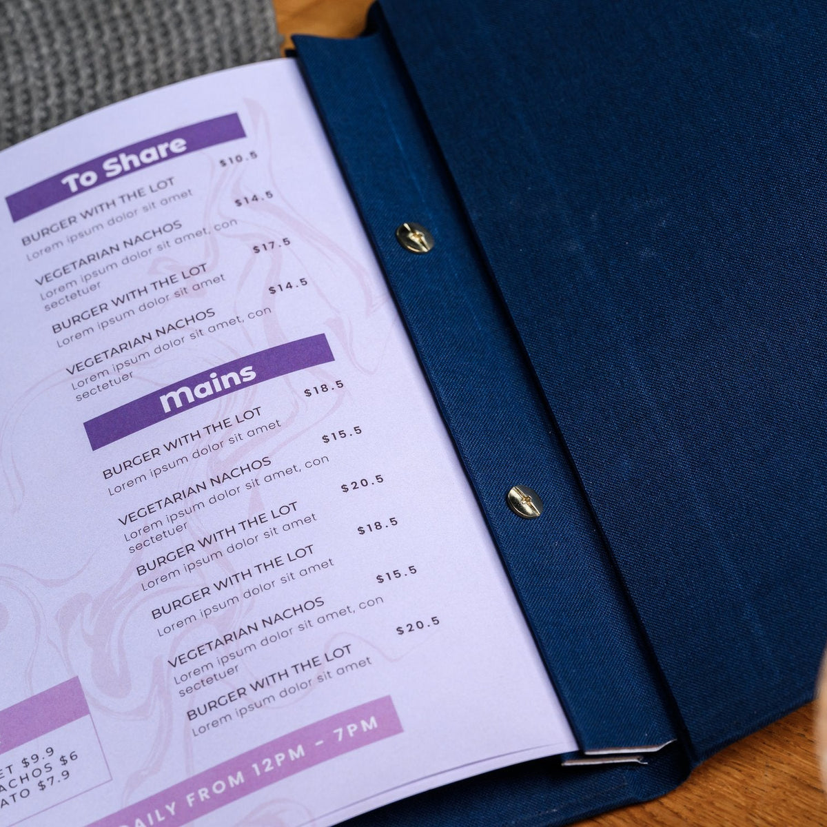 Open navy textile menu folder shown from the side with a purple and white printed menu list on the table