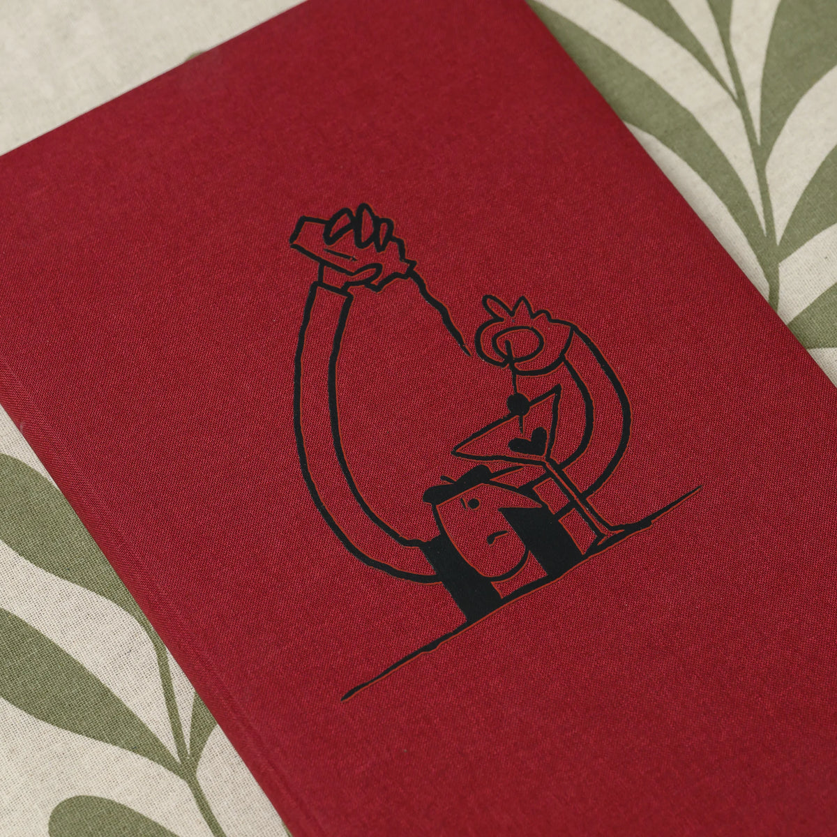 Close-up of a black DTF printed line drawing of a figure with a cocktail glass on the front of a red fabric cover