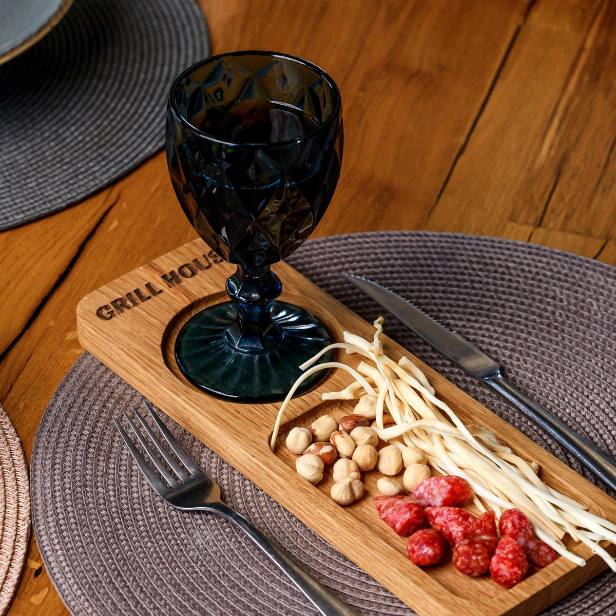 Oak GRILL HOUSE serving board with blue wine goblet in round recess and charcuterie of salami and hazelnuts in tray