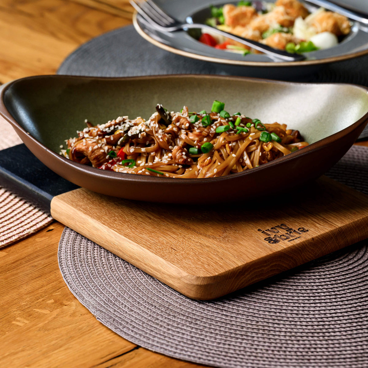 Close-up of black painted handle on two-tone oak snack serving board showing round hanging cutout and paint edge