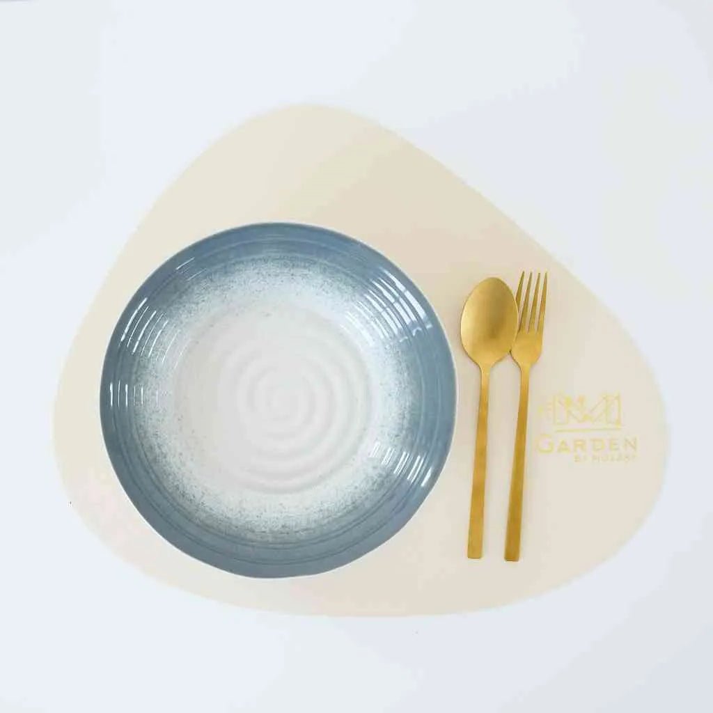 Beige teardrop-shaped faux leather placemat on a modern dining table

