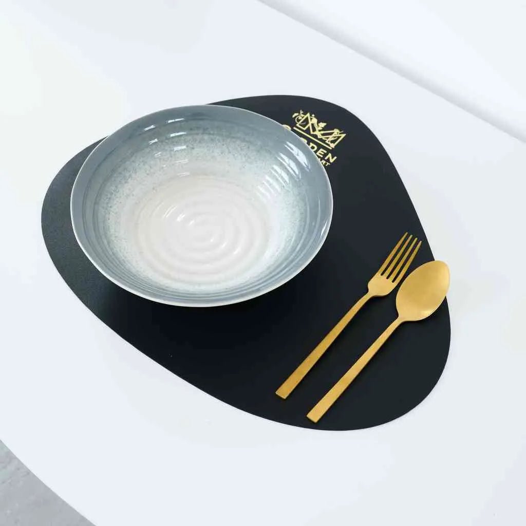 Close-up of black teardrop-shaped placemat showing smooth faux leather texture and stitching
